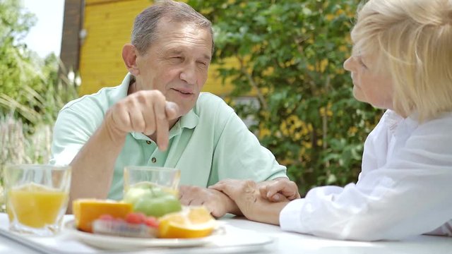An elderly couple talking in the garden for lunch.