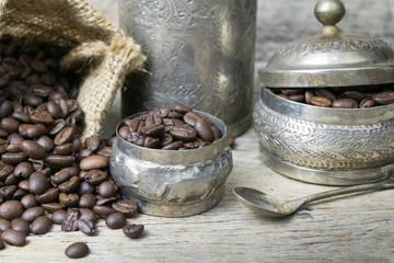 Silver cup and Coffee beans in sackcloth bag on wooden backgroun
