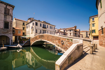 Typical bridge across a canal in Chioggia, Venice, Italy. - obrazy, fototapety, plakaty