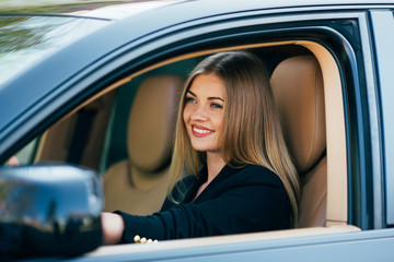 Fototapeta na wymiar Attractive business woman with sunglasses smiling and driving her car.