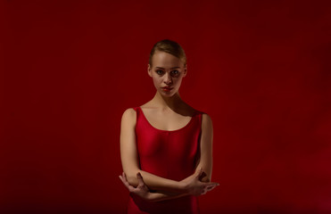 Fototapeta na wymiar Beautiful expressive dancer in red outfit, studio shot on red background