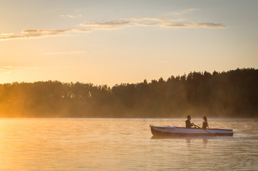 Romantic golden river sunset. Couple on boat backlit by sunlight
