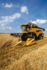 Obraz premium Yellow combine harvester at grain harvest