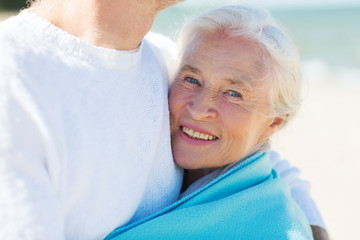 happy senior couple hugging on summer beach