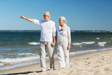 happy senior couple walking on summer beach