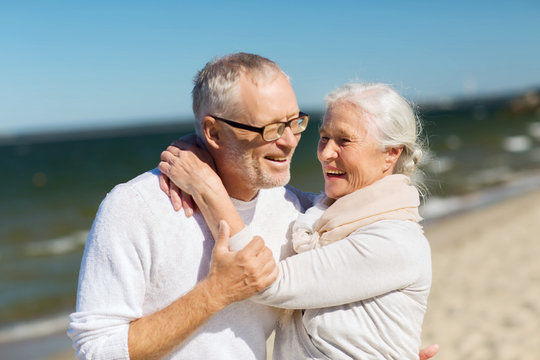 happy senior couple hugging on summer beach