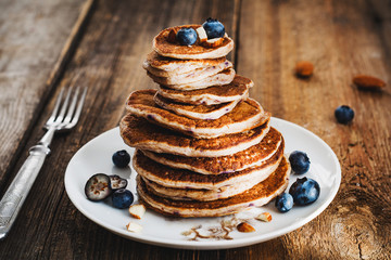 Whole wheat blueberry pancakes stack on a plate, wooden background