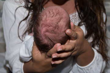 Naklejka premium Mother holding head of her newborn son in hands.