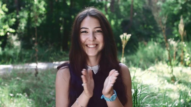 pretty girl claps her hands and rejoices in the forest