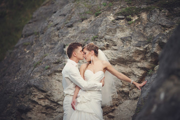 Groom kisses bride tender standing between the rocks