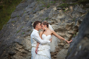 Tender wedding couple hugs between the rocks