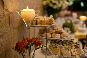 Ball candle stands in the high vase above cut sweets on the coff