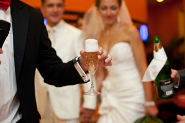Man holds a glass full of champagne and foam