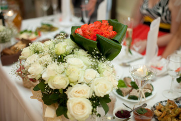 Red wedding bouquet stands on the dinner table