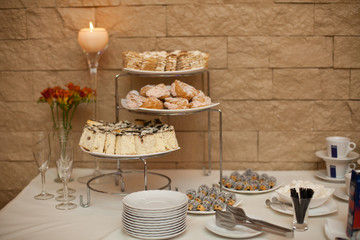 Cut sweets lie on the coffe buffet at the brick wall