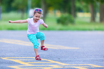 Girl is playing hopscotch game on the asphalt