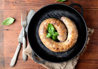 homemade sausages in a pan on a wooden background 