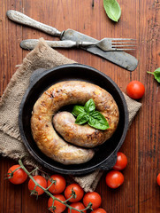 homemade sausages in a pan on a wooden background 