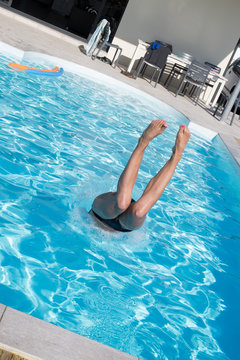 Girl preparing to dive into swimming pool at summer