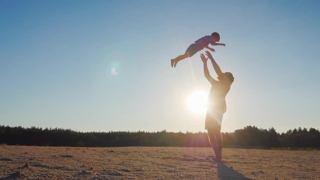 Strong father lobbed son in the sky. Playing with him at sunset