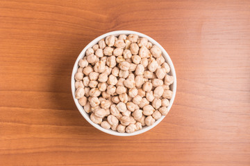 Raw Chickpeas into a spoon over a wooden table. 