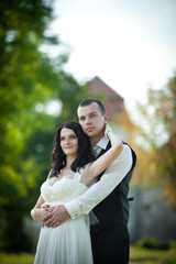 Fototapeta premium Stunning bride with black curly hair leans to a groom while he h