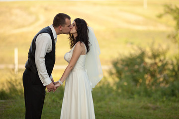 Tall groom bends to the bride for a kiss while standing on the f