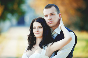 Obraz premium Black haired brude with blue eyes leans to the groom while he hu