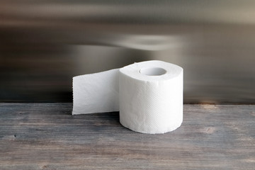 Roll of toilet paper on wooden table against steel background