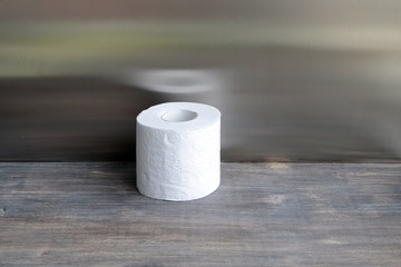 Roll of toilet paper on wooden table against steel background
