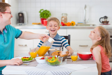 Smiling family eating breakfast in kitchen