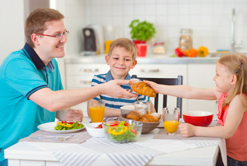 Obraz na płótnie Canvas Smiling family eating breakfast in kitchen