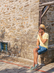 Young hipster man eating a fresh fig in the old village