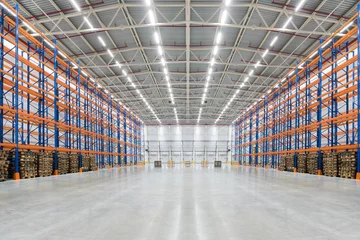 Foto op Aluminium Industrieel gebouw Leeg enorm distributiemagazijn met hoge planken en pallets