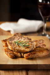 pork chop on wooden board with rosemary