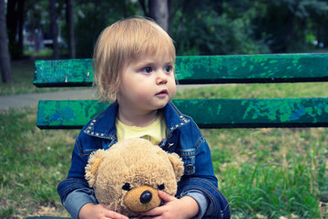 Toddler sitting on the bench in the park