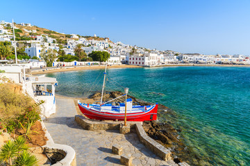 Fishing boat on coastal promenade and view of beautiful beach with turquoise sea water, Mykonos...