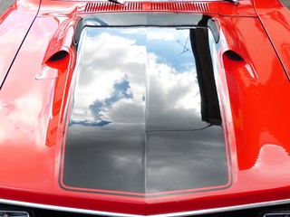 Spiegelung der Wolken in einer glänzenden Motorhaube eines roten amerikanischen Sportwagen der...