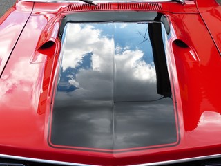 Regenwolken spiegeln sich in der glänzenden Motorhaube eines roten amerikanischen Coupé der...