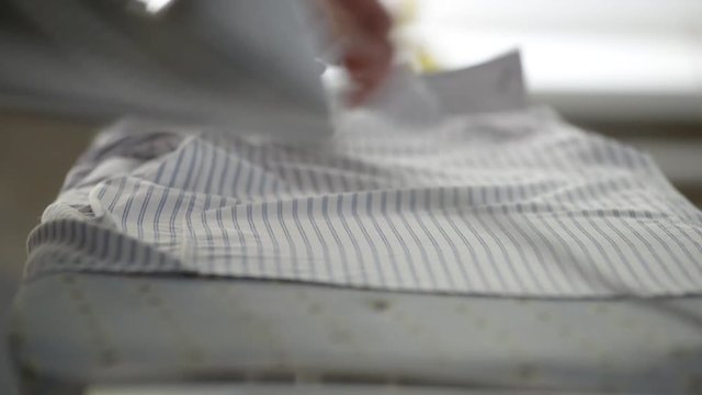 Man irons the shirt on the ironing board, close-up, blurred background