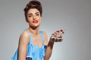 Fotobehang Picture of beautiful pin-up girl holding cake in hands at studio © Cookie Studio