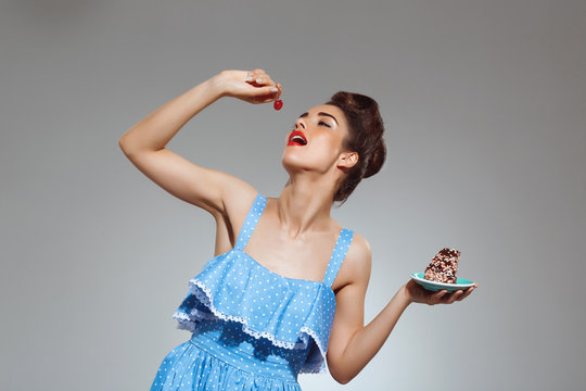 Picture of beautiful pin-up girl eating cake at studio