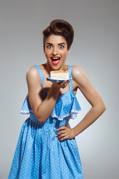 Picture of beautiful funny pin-up girl holding cake in hands at studio