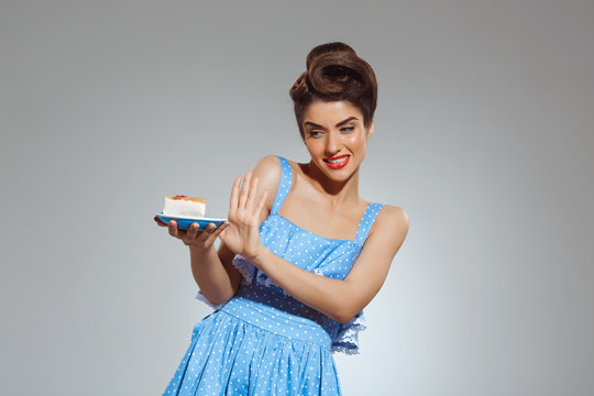 Picture of beautiful pin-up girl refusing eating cake at studio