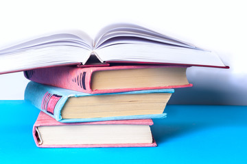 Open book, stack of colorful hardback books on light table. Back