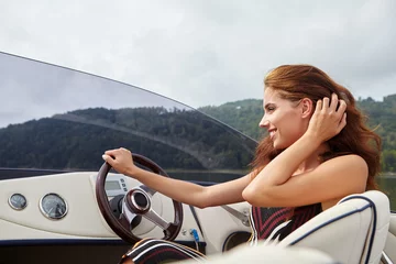 Abwaschbare Fototapete Sommerurlaub - junge Frau, die ein Motorboot fährt © ZoomTeam