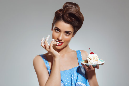 Picture of beautiful pin-up girl eating cake at studio