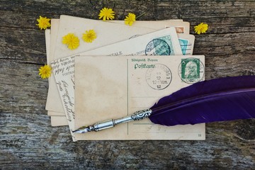 alte leere Vintage Postkarte mit alter Briefmarke liegt auf altem Holz mit gelben Blüten und...