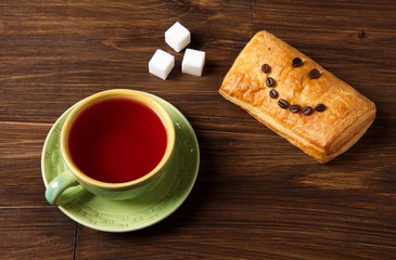 Green cup of red tea with white sugar cubes and puff with a smile of coffee grains