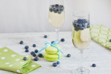 Glasses of champagne with blueberries and green macaroons